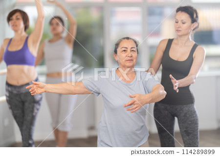 Adult woman teacher correcting beginning dancers Adult woman teacher correcting beginning dancers 114289899