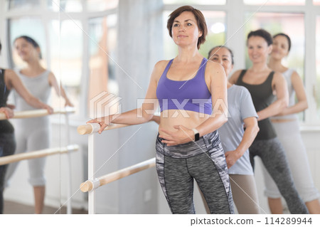 Woman mastering battement tendu at barre in ballet class for beginners 114289944
