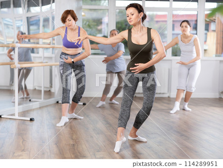 Woman leading ballet class with female amateur dancers in studio 114289951