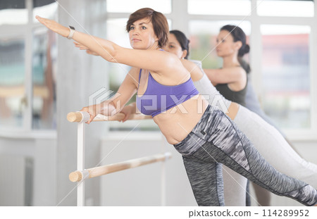 Middle aged woman learning arabesque in ballet class for beginners 114289952