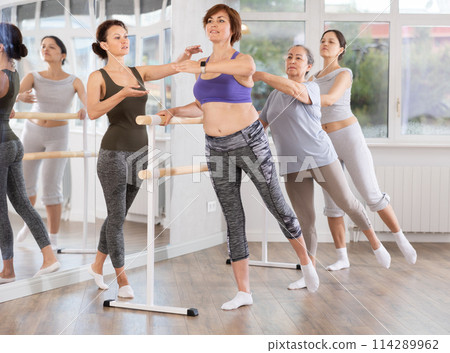 Adult woman teacher correcting beginning dancers Adult woman teacher correcting beginning dancers 114289962