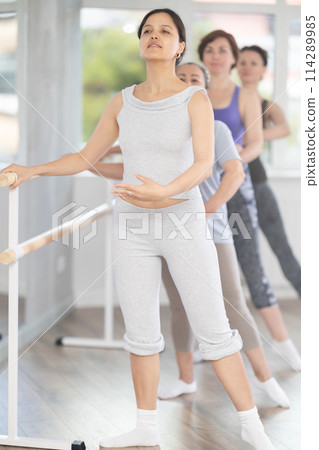 Group of amateurs of different ages practice ballet moves in classical dance class Group of amateurs of different ages practice ballet moves in classical dance class 114289985