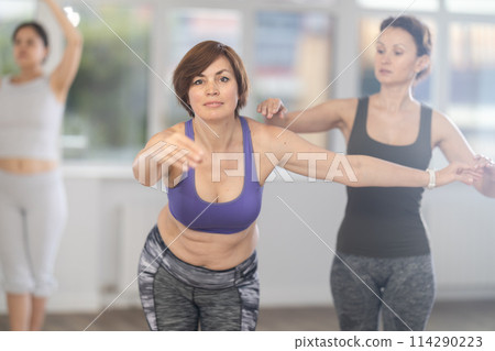 Adult woman teacher correcting beginning dancers Adult woman teacher correcting beginning dancers 114290223