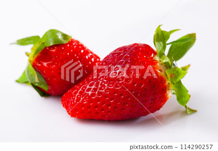 Large ripe bright red strawberries lie on white background 114290257