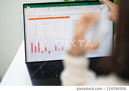 一位女士打開電腦並用智慧型手機交談 一位女士打開電腦並用智慧型手機交談 114290308