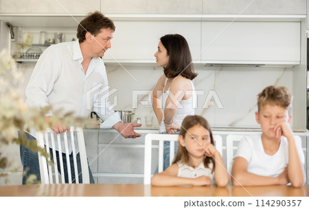 Parents quarrel behind back of blurred unrecognizable son and daughter. 114290357