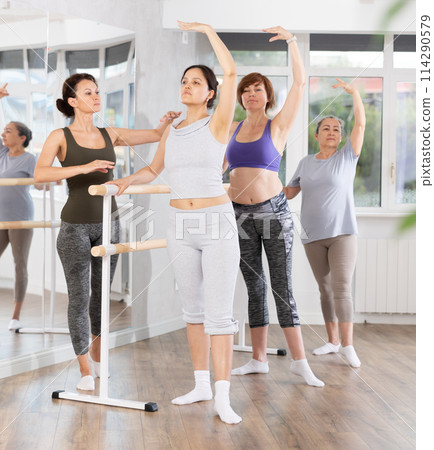 Adult woman teacher correcting beginning dancers 114290579