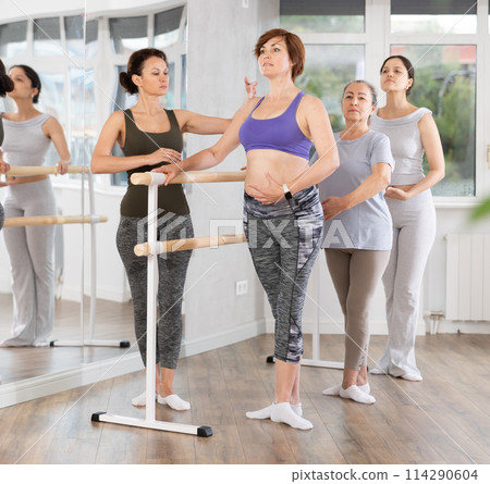 Female ballet enthusiasts mastering basic positions with teacher Female ballet enthusiasts mastering basic positions with teacher 114290604