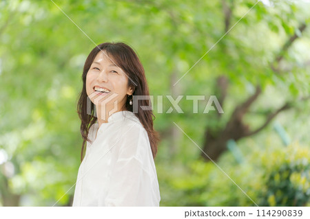 穿著白襯衫的中年婦女在大自然中微笑 114290839
