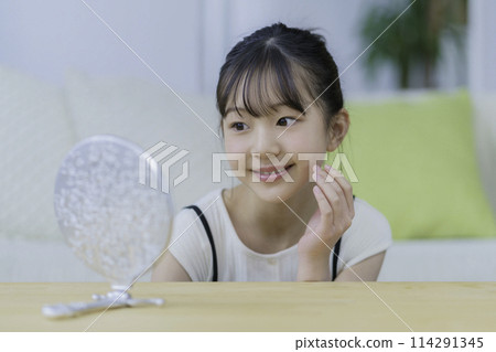 微笑的小女孩看著鏡子，摸著臉頰 114291345