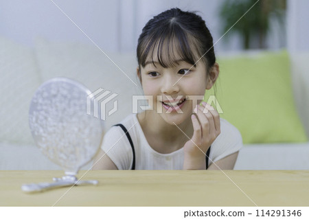 微笑的小女孩看著鏡子，摸著臉頰 114291346