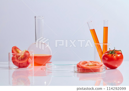 Front view photo on white background at laboratory scene, decorated by ripe tomato and red fluid extract from it. Tomatoes are a source of beta-carotene, lycopene, and vitamin C Front view photo on white background at laboratory scene, decorated by ripe tomato and red fluid extract from it. Tomatoes are a source of beta-carotene, lycopene, and vitamin C 114292099