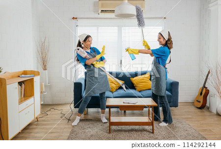 Asian maid joyful cleaning, vacuum as guitar husband playful twist. Singing dancing happily. Music-filled service brings excitement to household chores. Cleaning is fun Asian maid joyful cleaning, vacuum as guitar husband playful twist. Singing dancing happily. Music-filled service brings excitement to household chores. Cleaning is fun 114292144
