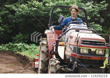 一個男人騎著拖拉機，一個女人看著他 114293229