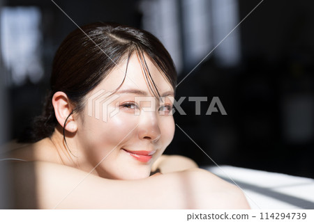 一位美麗的年輕女子的特寫，她有透明感和光澤感，灰色背景，看著相機 114294739