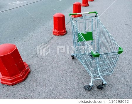 Empty shopping cart on the road with red traffic cones in the background Empty shopping cart on the road with red traffic cones in the background 114298052