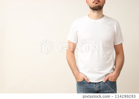 A young guy in a white T-shirt on a light background 114299293