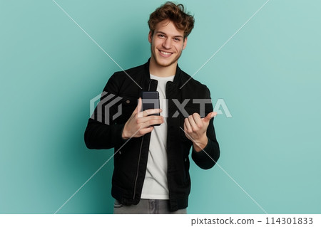 Cheerful sporty red-haired guy shows a finger on the smartphone screen on a blue background. 114301833