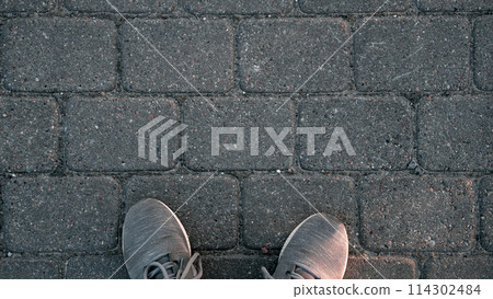 A person's feet are on a brick sidewalk A person's feet are on a brick sidewalk 114302484