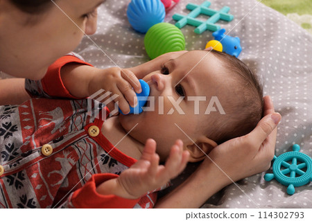 Cute adorable newborn baby playing with colorful rattle toy. baby with teether. six months old lovely baby portrait on white with teether toy 114302793