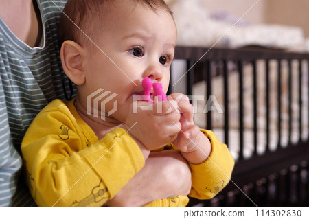 Cute adorable newborn baby playing with colorful rattle toy. baby with teether. six months old lovely baby portrait on white with teether toy 114302830
