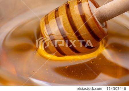 Close-up of honey in a glass container and honey dipper 114303446