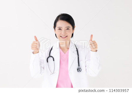 Middle-aged woman in white coat thumbs up 114303957