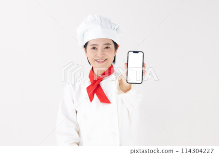 Middle-aged woman, chef uniform, smartphone Middle-aged woman, chef uniform, smartphone 114304227