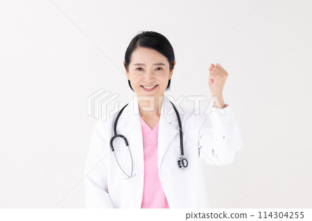 Middle-aged woman in white coat giving a fist pump 114304255