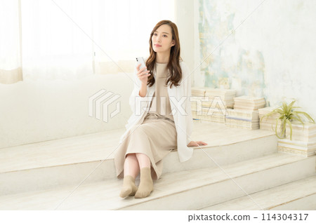 A woman looking at her smartphone indoors 114304317