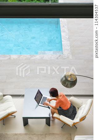 Senior digital nomad woman working at luxury villa in Phuket. andaman sea as background. Senior digital nomad woman working at luxury villa in Phuket. andaman sea as background. 114304537