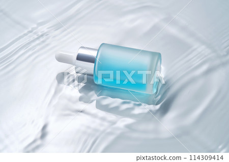 Bottles of cosmetics with a dropper in water on a blue background. Bottles of cosmetics with a dropper in water on a blue background. 114309414