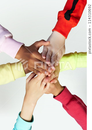 Close up of children's hands giving a high five in collaboration for mission, goal or team building together against grey background. 114310692