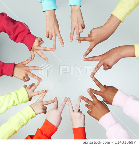 Close up of children's hands showing peace sign and standing in circle against grey background. Gestures. 114310697