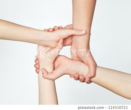 Group of children's hands holding on to each other, symbolizing work in team and support against grey background. Group of children's hands holding on to each other, symbolizing work in team and support against grey background. 114310721
