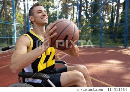 Handsome man with disability playing basketball in wheelchair Handsome man with disability playing basketball in wheelchair 114311284