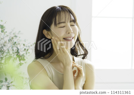 一位微笑的年輕女子的肖像，手放在臉頰上，閉著眼睛 114311361