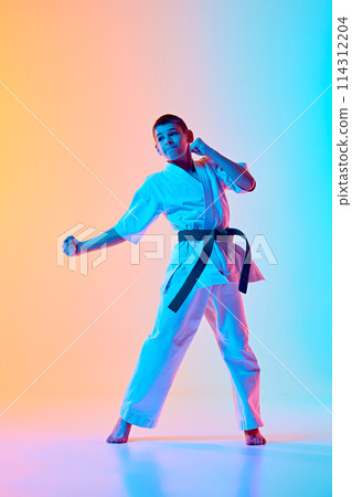 Dynamic martial arts pose, teen boy in motion, training against gradient orange blue background in neon light Dynamic martial arts pose, teen boy in motion, training against gradient orange blue background in neon light 114312204