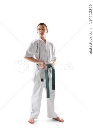 Full-length image of teen boy, karate athlete posing in white kimono with green belt isolated on white studio background Full-length image of teen boy, karate athlete posing in white kimono with green belt isolated on white studio background 114312296