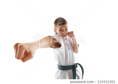 Taekwondo kick performed by determined young karate athlete in white kimono and green belt isolated on white studio background 114312301