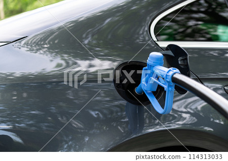 Close up of fuel cell car with connected hydrogen fueling nozzle. 114313033