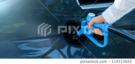 Man holds a hydrogen fueling nozzle. Refueling car with hydrogen fuel. Concept. Man holds a hydrogen fueling nozzle. Refueling car with hydrogen fuel. Concept. 114313083