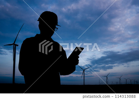 Silhouette of engineer with tablet computer and wind turbines at sunset Silhouette of engineer with tablet computer and wind turbines at sunset 114313088
