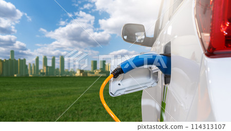 Close up of electric car with a connected charging cable on the background of green eco city 114313107