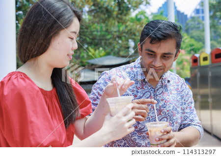 International couple drinking cold drinks outdoors International couple drinking cold drinks outdoors 114313297