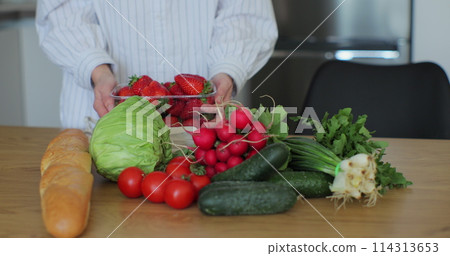 Woman put a bag of groceries on the kitchen table. Women hands put vegetables and and fruits on the table. Woman put a bag of groceries on the kitchen table. Women hands put vegetables and and fruits on the table. 114313653