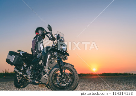 A motorcycle rider watching the sunset 114314158