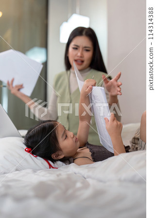 Asian woman working from home, stress and busy over her work with her pretty young daughter enjoying her time with her mother Asian woman working from home, stress and busy over her work with her pretty young daughter enjoying her time with her mother 114314388