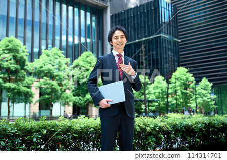 Businessman standing with a laptop in an office building 114314701