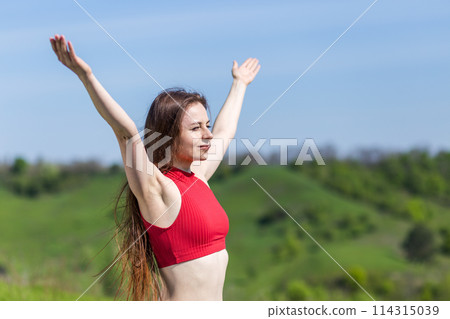Young fitness woman throwing her arms wide open feeling freedom at outdoor 114315039